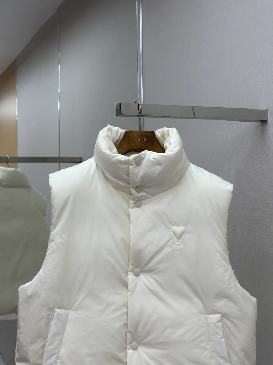 P810 AMIPARIS love padded embroidered down vest Fabric selection: Taffeta fabric woven from 100% polyester fiber. It adopts warp and weft plain weave and is woven very tightly, making the surface of the fabric extremely smooth and flat, with a "skinny" and stiffness that is not easy to collapse. When rubbed or moved around, it will make a unique, crisp "rustling" sound. At the same time, it has a delicate plain texture and a soft, elegant silky luster. This kind of luster is not as dazzling as satin, but more restrained and advanced.  Lining selection: Use 100% nylon to create the lining. The high-density and tight weaving process prevents tiny lint from getting out of the gaps in the fabric. The smooth surface improves the putting on and taking off experience, and the excellent wear and tear resistance ensures damage caused by frequent use, while the light and soft texture does not affect the overall weight.  Technology: The fabric and padding material are tightly fixed on the frame of the embroidery machine. The embroidery machine uses sparse stitches along the padding layer to outline the filling area of the pattern, and then runs the overlay layer's padding, using dense stitches to perfectly cover the foam padding layer, thus forming a slightly raised love embroidery, which feels soft and full, enhancing recognition while maintaining a low profile. High-quality filling: It uses 90 white duck down with a weight of 160g to ensure excellent thermal insulation performance. After strict screening and processing, the velvet is not easy to get drilled, ensuring durability.  Accessories: One-to-one customized three-standard, one-to-one customized hem elastic buckle, one-to-one customized snap button SIZE: XS S M L
